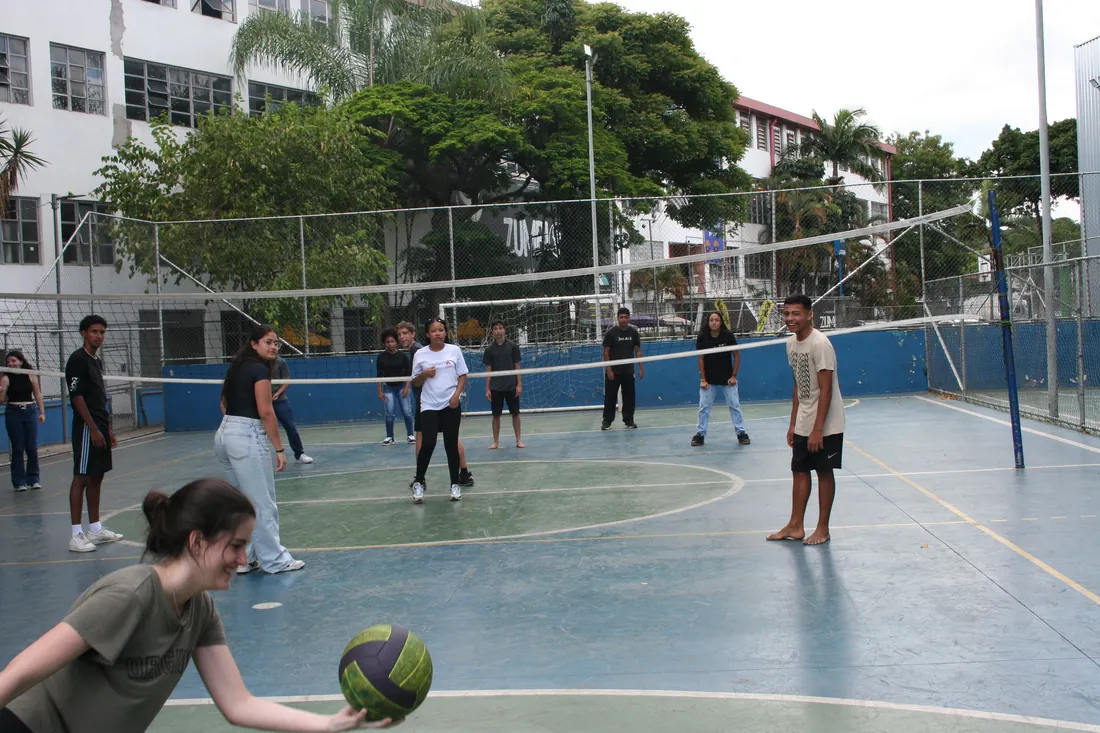 Jovens jogando vôlei em uma quadra, em registro de esporte da juventude